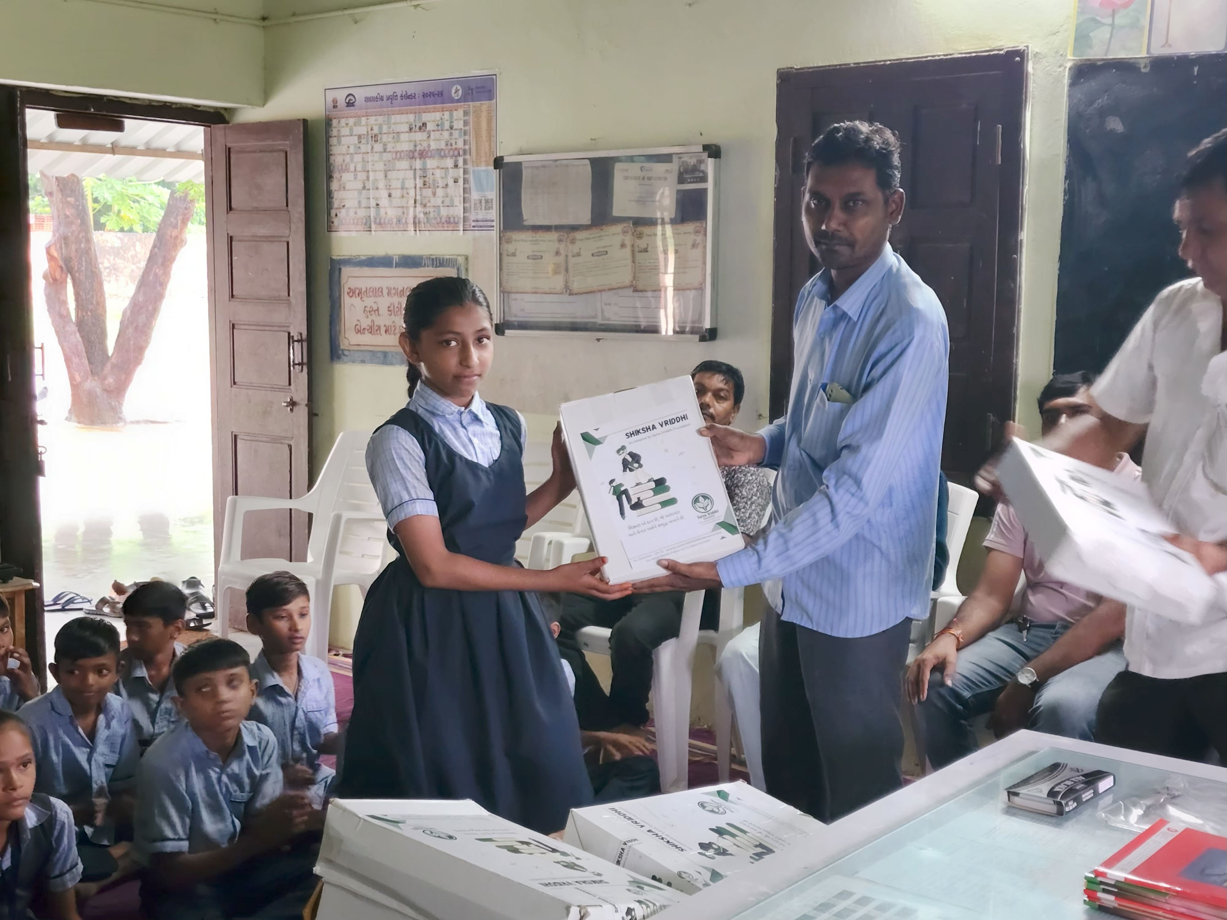 Girl receiving educational kit from a man in light blue shirt
